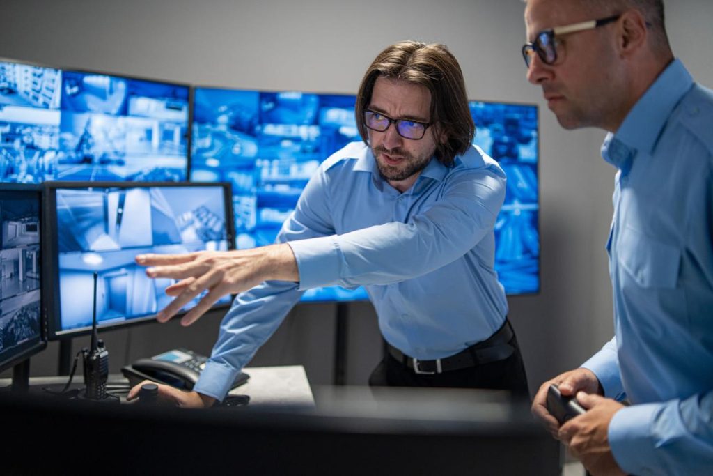 Beveiligingsmedewerker in monitoringcentrum met camerabeelden en digitale schermen